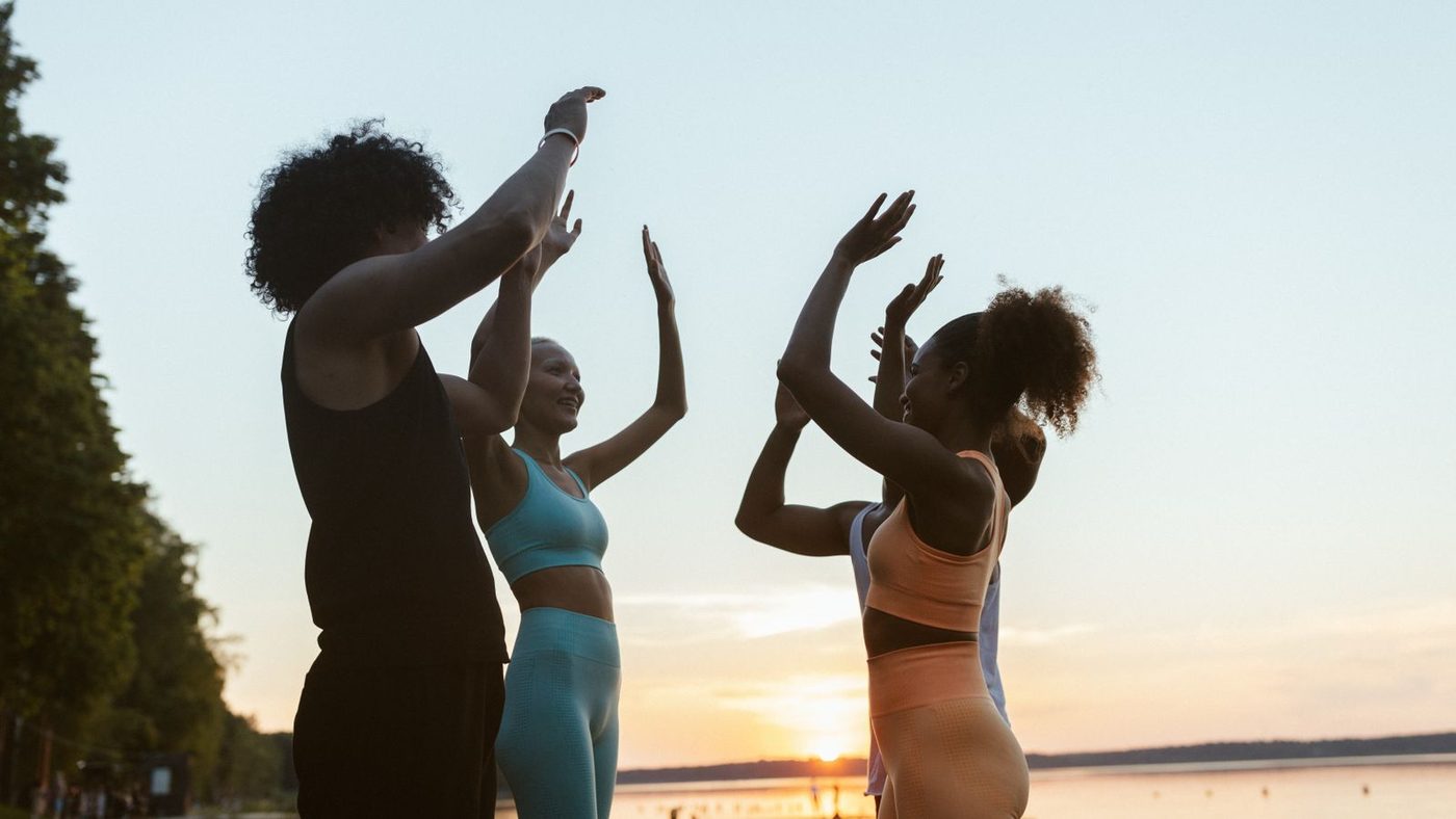 Women exercising together on the beach at sunset